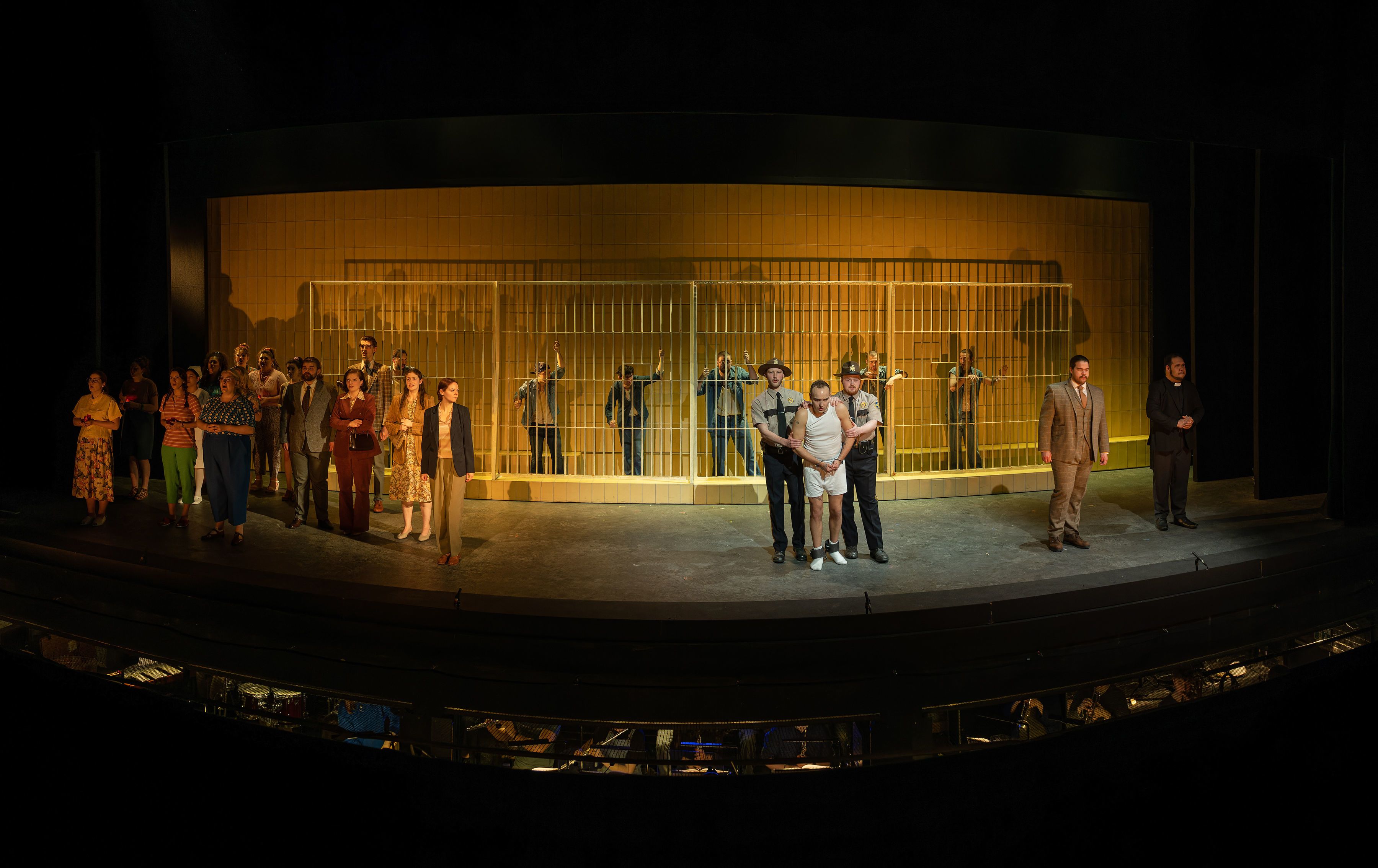 crowds at a prison, with some inmates behind bars and a prisoner restrained by guards